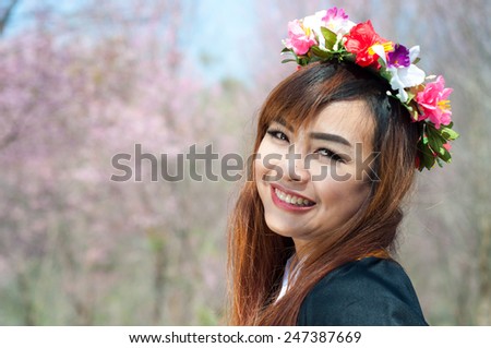 Beautiful female graduate wearing graduate grown and flower wreath