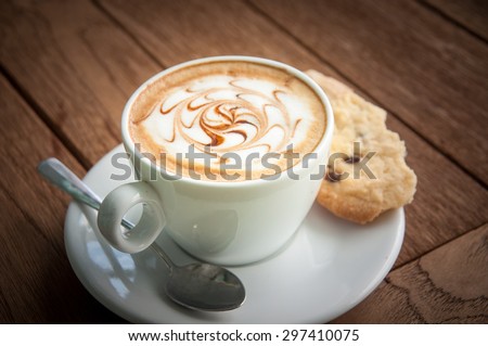 Hot coffee and cookie on saucer with wooden background