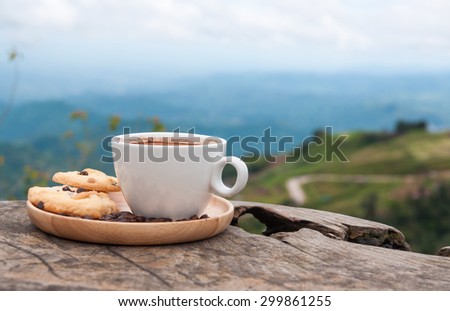 White coffee cup and cookies on wooden table with beautiful mountain view