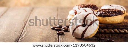 Glazed mini donuts with coffee candies on wooden background. Party food concept with copy space. Banner.