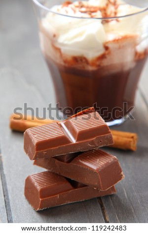 Chocolate pieces with chocolate milkshake and cinnamon stick on wooden background