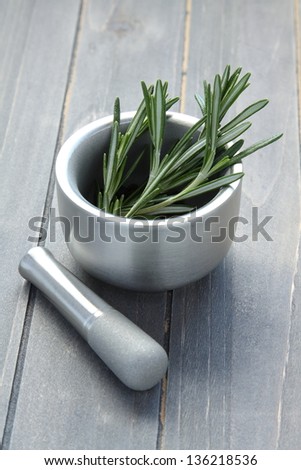 Metal mortar and pestle with rosemary on wooden background