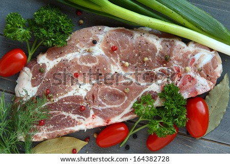 Fresh raw pork shoulder chop with spices and vegetables