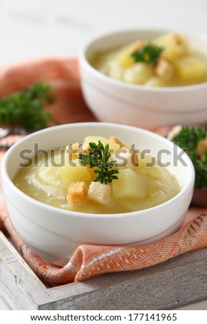 Bowl of creamy sweet potato soup with croutons on wooden tray