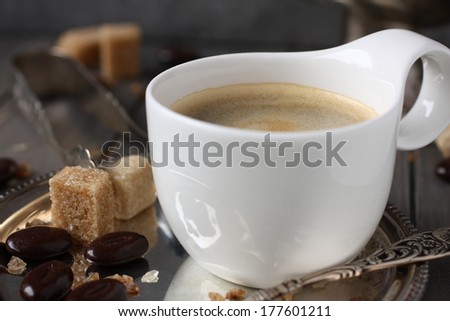 Cup of coffee, sugar cubes and chocolate candy on old wooden background