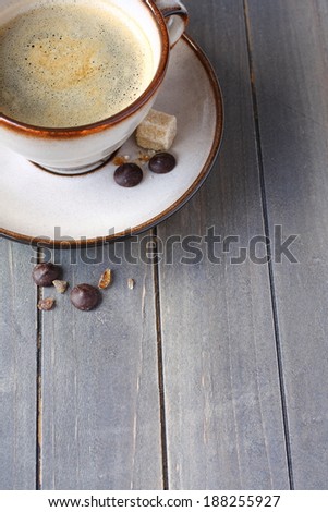 Cup of coffee, sugar cubes and chocolate drops on old wooden background with copy space