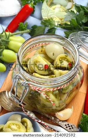 glass jar with pickled green tomatoes prepared for winter