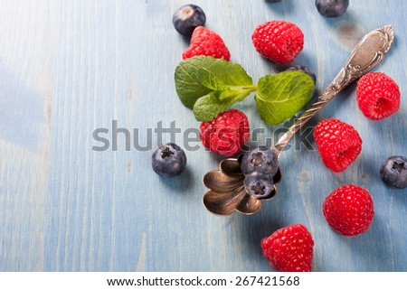 Berries on Blue Wooden Background. Summer or Spring Organic Berry over Wood. Raspberries, Blueberry, Vintage Spoon and Mint. Agriculture, Gardening, Harvest Concept. Copy space.