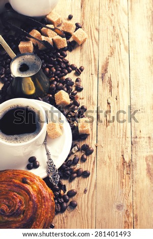 Old coffee pot, cup of coffee and coffee beans on wooden rustic background. Selective focus. Toned