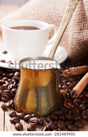 Old coffee pot with coffee beans and cinnamon sticks on wooden rustic background. Selective focus.