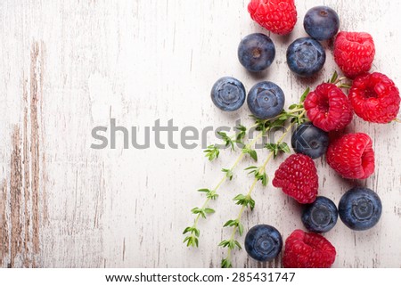 Berries on White Wooden Background. Summer or Spring Organic Berry over Wood. Raspberries, Blueberry and thyme. Healthy food, Gardening, Harvest Concept. Copy space.