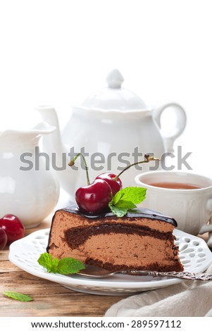 Piece of delicious chocolate mousse cake with cherries and mint over white with copy space. High tea concept. Selective focus. Space for text.