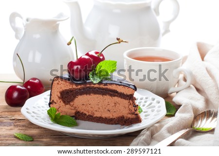 Slice of delicious chocolate mousse cake with cherries and mint over white. High tea concept. Selective focus.