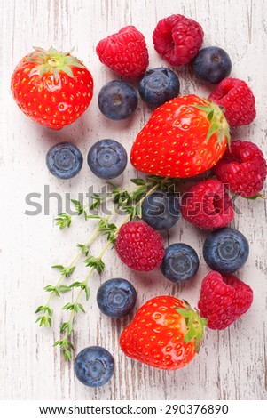 Close up of strawberry and other berries on White Wooden Background. Summer or Spring Organic Berry over Wood. Strawberries, Raspberries, Blueberry and thyme. Healthy food, Gardening, Harvest Concept.