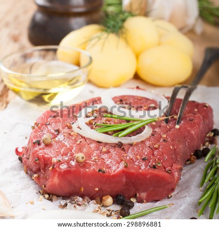 Stack of raw beef steaks and spices on old wooden background.  Healthy food concept. Selective focus.