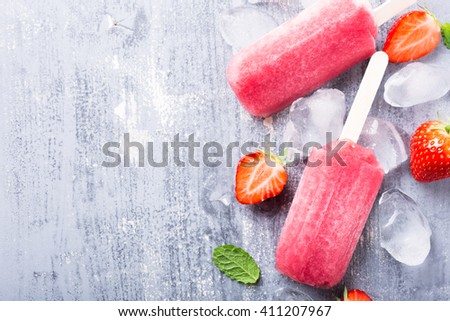 Homemade strawberry popsicles with ice and berries. Summer food concept with copy space for text. Top view.