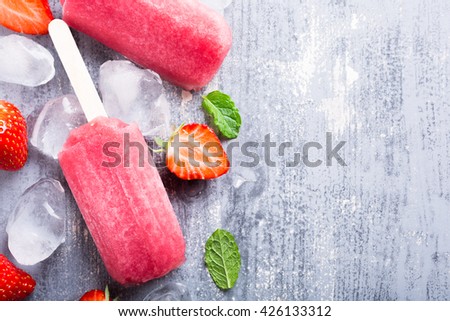 Homemade strawberry popsicles with ice and berries. Summer food concept with copy space for text. Top view.