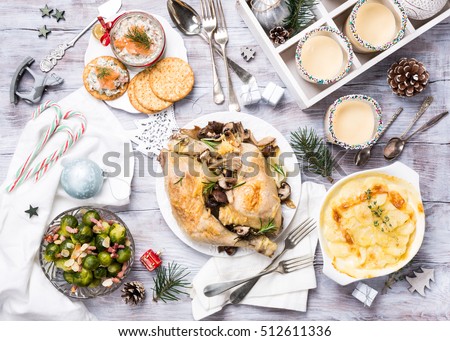 Delicious Christmas themed dinner table with roasted chicken, appetizers and desserts. Top view. Holiday concept.