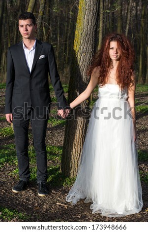 portrait of young newly married couple holding hands in the forest
