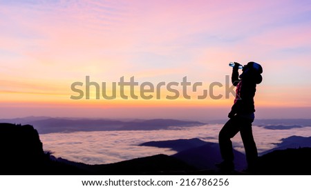 girl drinking water on the top of the mountain in the sunrise