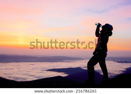 girl drinking water on the top of the mountain in the sunrise