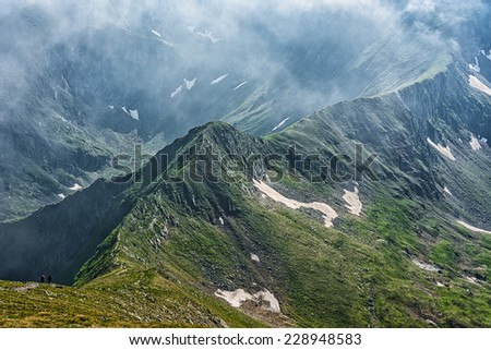 hikers on a remote mountain ridge under a foggy sky