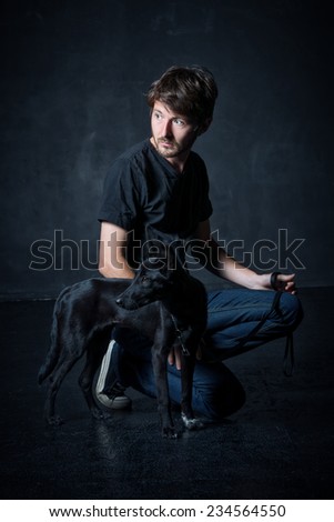 studio portrait of young man and his black dog