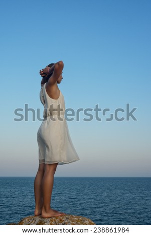 Young woman watching the sea and relaxing on a cliff