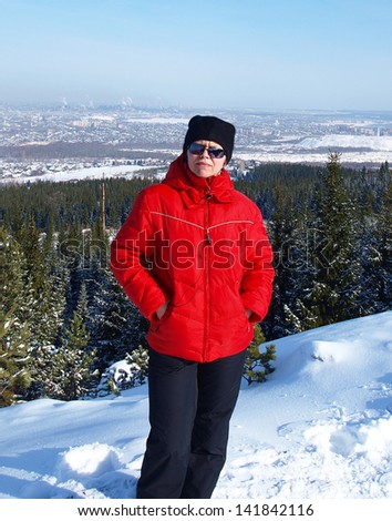 Woman in sports clothes and sunglasses on the background of the winter city