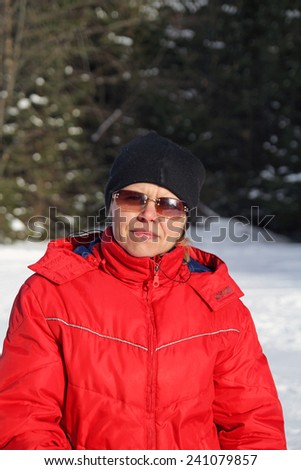 Woman in sports clothes and sunglasses on the background of the winter forest