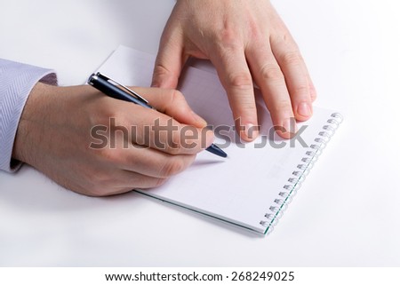 Businessman takes notes in a notebook. Hand writes a pen in a notebook