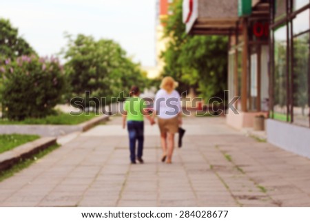 Blurred mother and son walking in an alley holding hands