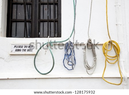A bell ropes, hanging on the wall of the church with a sign that tells people not ring the bell