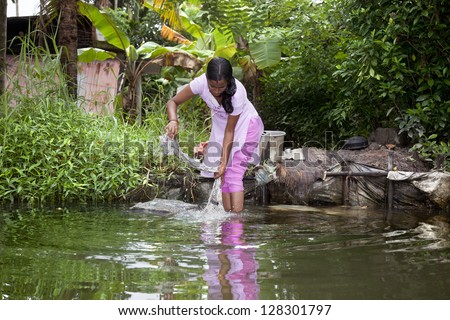ALLEPY-SEPTEMBER 2012: An Indian woman washes her clothes on a rock in one of the canals around Alappuzha on september 7, 2012 in Allepy, India.