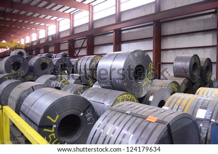 Rolls of Steel are waiting to be further processed in a manufacturing plant.