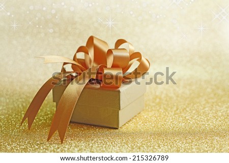 Christmas gift on Decorative background in gold with sparkling stars