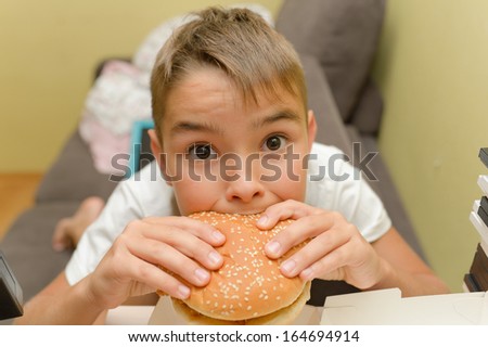 little caucasian boy eating burger