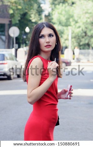 Girl with a cigarette in one arm and a cigarette pack in other turns around back