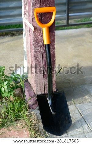 Shovel is in the yard, leaned against a wooden column
