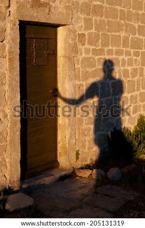 Shadow of man opening door at Lubenice - Croatia