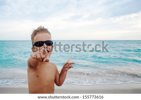 young boy pointing with his finger on sea