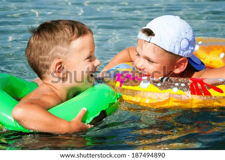 two three years boys in a swim ring have fun in sea