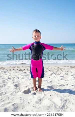 small boy in his diving suit smiling at the beach