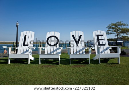 Giant lawn chairs sitting in a public park inscribed with letters spelling LOVE.