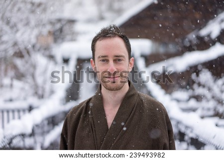 Western man in Japanese Yukata during winter snow on old wooden bridge