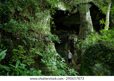 Man exploring old stone mine deep in lush green jungle