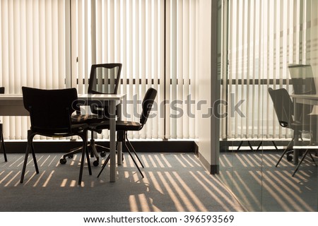 Office interior with light shining through window blinds