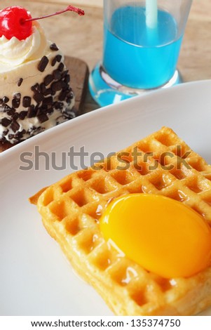 Waffle topped with eggs and cake.