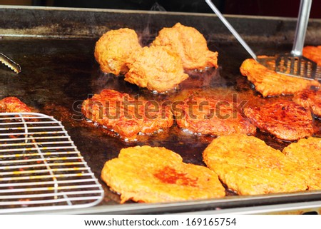 Fried steak on a hot pan on the market.