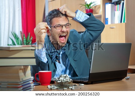 Young angry businessman working on his laptop at home
